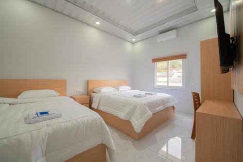 龙目岛库塔Lombokhouse Mandalika的一间白色卧室,配有两张床和窗户