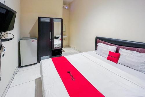 泗水RedDoorz At Graha 99 Simomulyo的一间卧室配有一张带红色毯子的大床