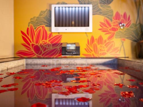 神户HOTEL　Noblesse的墙上挂着红色鲜花的桌子的房间
