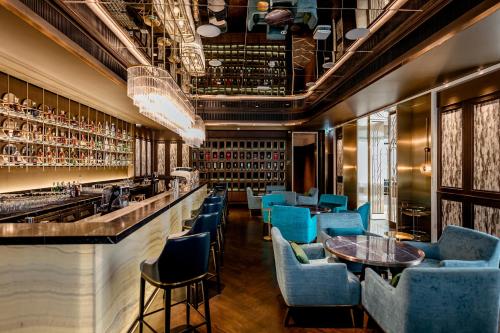 曼谷SILQ Hotel & Residence, Managed by The Ascott Limited的一间酒吧,餐厅内摆放着蓝色的椅子和桌子