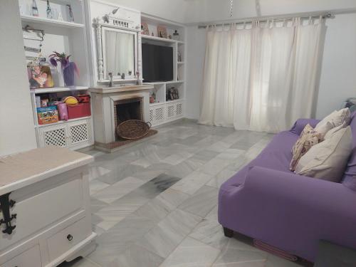 EsteponaMoraleja, habitación en bajos con jardín en Estepona的客厅配有紫色沙发和壁炉