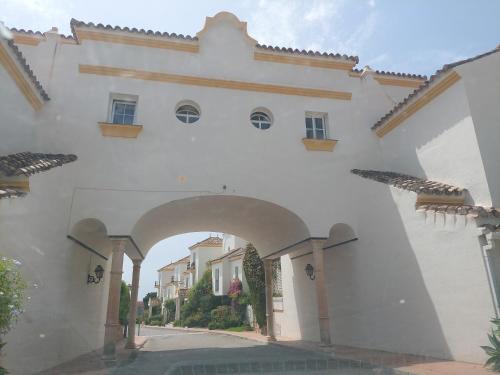 EsteponaMoraleja, habitación en bajos con jardín en Estepona的街道上带有拱门的白色建筑