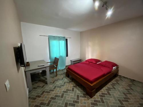 MamoudzouRésidences Gamly的一间卧室配有红色的床、一张书桌和一台电视。