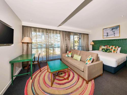 悉尼Peppers Manly Beach的一间卧室配有一张床、一张沙发和一张桌子