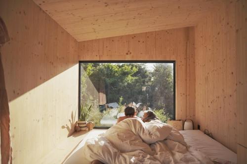 金瓦拉Slow Cabins Kinvara的一对夫妇躺在窗户房间里