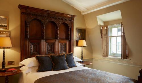 伦敦巴蒂兰利酒店的一间卧室配有一张大床和木制床头板