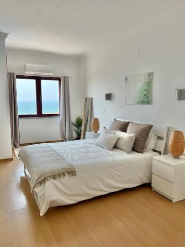 埃里塞拉Ribeira DIlhas Beach Apartment的白色的卧室设有一张大床和一个窗户