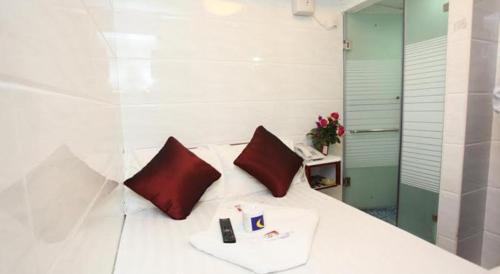 香港Relaince Inn的一张带两个红色枕头的白色床