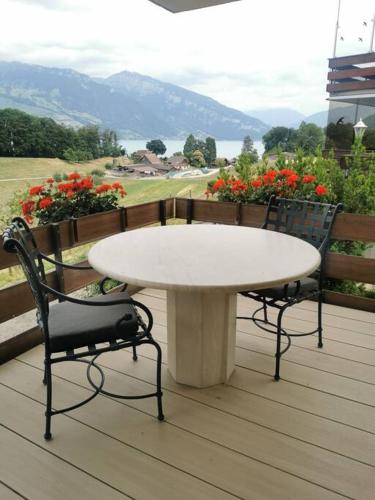 EinigenNEB-THUN Einigen, Wohnung am See的花卉甲板上的一张白色桌子和两把椅子