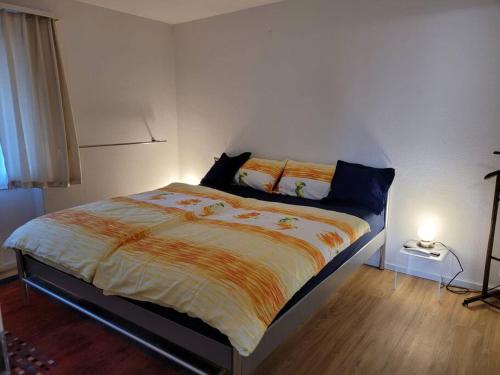 EinigenNEB-THUN Einigen, Wohnung am See的一间卧室配有一张带橙色和白色棉被的床