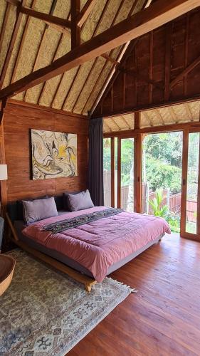 PereanRUMAH KAYU MATARAJA VILLA - TABANAN的木制客房内的一间卧室配有一张大床