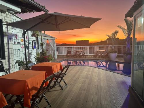 里约热内卢Hotel Pousada Irmaos Freyhardt的一个带桌子和遮阳伞的庭院和一个游泳池