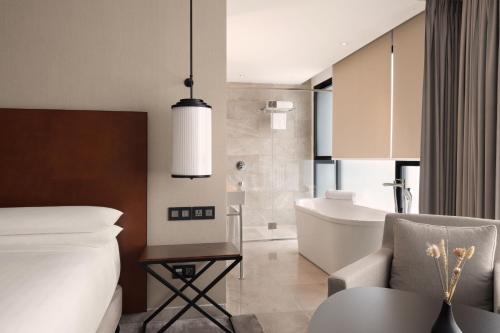 突尼斯Tunis Marriott Hotel的一间卧室配有一张床,浴室设有浴缸