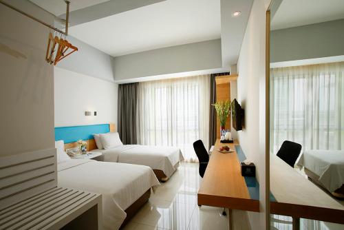 加拉旺BATIQA Hotel & Apartments Karawang的酒店客房设有两张床和一张桌子。