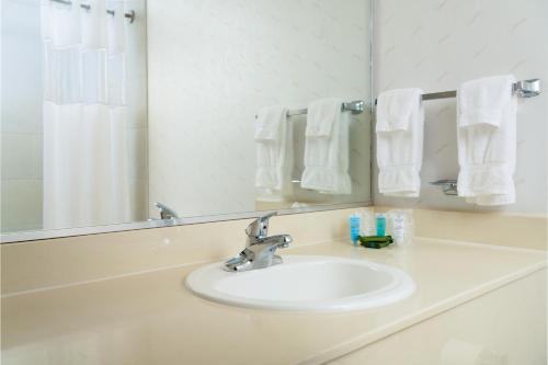 博蒙特MCM爱莱高特酒店与会议中心的浴室水槽配有镜子和白色毛巾