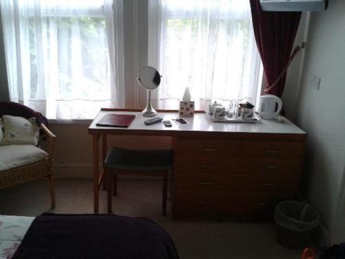普里茅斯卡拉尼尔旅馆的一间卧室配有一张桌子、一盏灯和一扇窗户