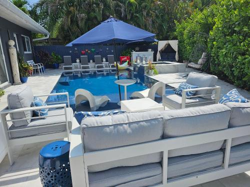 劳德代尔堡Casa806 Men Only Guest House的一个带椅子的庭院和一个带蓝伞的游泳池