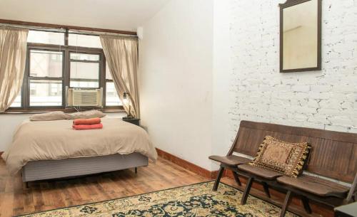 纽约Marvelous 3BR in NYC!的一间卧室设有一张床、一张长凳和砖墙