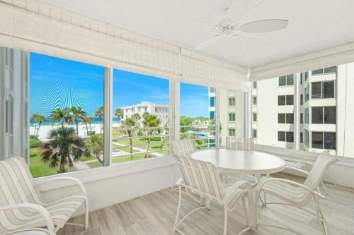 Point O'RocksIsland House Beach Resort 14S的客房设有桌椅和大窗户。