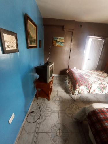 基多HOTEL EL PANECILLO-Tanta的一间卧室配有一张床和一张桌子上的电视