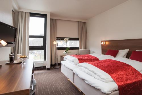 奥塔Thon Partner Hotel Otta的酒店客房设有一张大床和一张书桌。