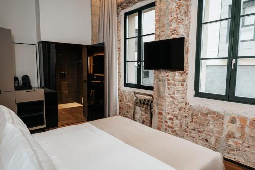 蒙达卡Hotel Luruna Palacio Larrinaga的卧室配有1张床和1台砖墙电视