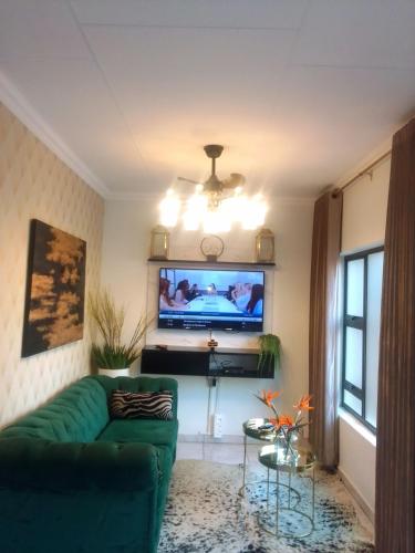 比勒陀利亚Elegant Airbnb的客厅配有绿色沙发和平面电视