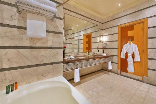 吉达吉达希尔顿酒店的带浴缸、两个盥洗盆和门上长袍的浴室