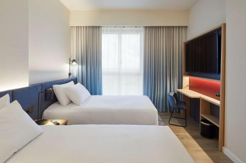 略夫雷加特河畔奥斯皮塔莱特Hampton By Hilton Barcelona Fira Gran Via的酒店客房设有两张床和电视。