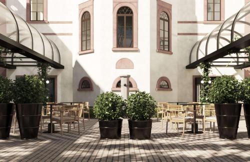 海德堡海德堡市中心皇冠假日酒店的建筑前方的庭院配有桌椅