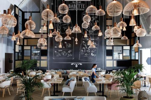 巴黎Hilton Garden Inn Paris La Villette的用餐室配有桌椅和吊灯。