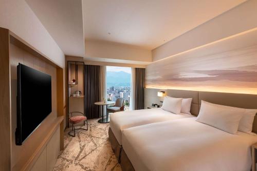 富山DoubleTree by Hilton Toyama的酒店客房设有两张床和一台平面电视。