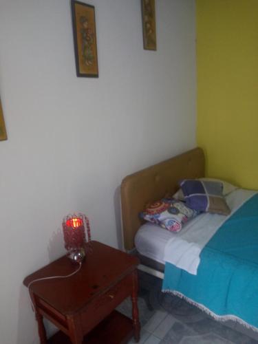 基多Hotel Tanta Wasi-Panecillo的一间卧室配有一张床和一张带台灯的桌子