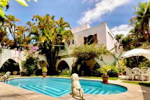 瓜鲁雅Casa aconchegante,perto da praia,com piscina,muito jardim,e pet friendly的棕榈树屋前的游泳池