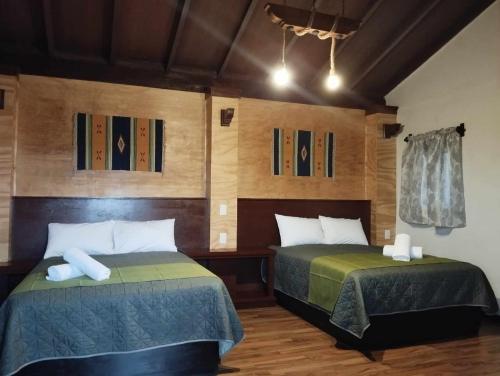 瓦曼特拉Hotel & Cabañas Malinche的木墙客房的两张床