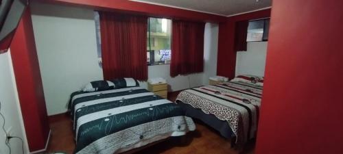 万卡约Hotel Águila Real的宿舍间的两张床,设有红色的墙壁和窗户
