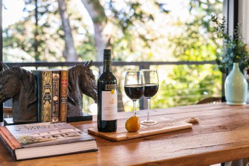 蒙特维尔Fig Tree Nest的木桌旁的一瓶葡萄酒和两杯酒