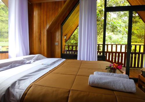 奥克萨潘帕Kusi Lodge的一间卧室设有一张大床和大窗户