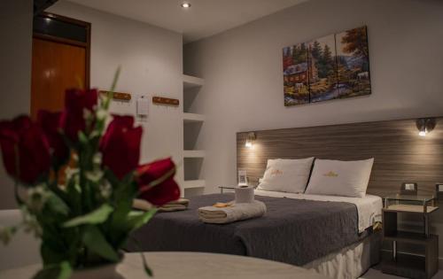圣维森特德卡涅特Millennium Hotel的酒店客房设有两张床和一张红玫瑰桌。