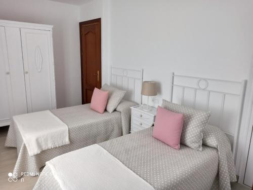马拉加Casa La Loma en Archidona的客房内的两张床和粉红色枕头