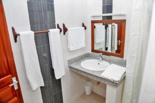 KwaleGalu Gardens Diani Beach ,Coastal Apartments by Nest & Nomad的浴室配有盥洗盆、镜子和毛巾