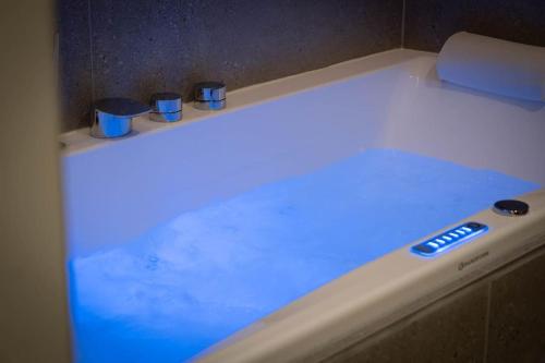 维希Villa La Roseraie的白色浴缸,上面有蓝色的灯光