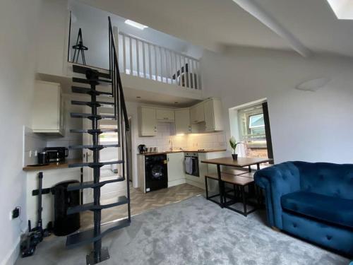 马特洛克Wards House Loft Apartment, Matlock的客厅设有蓝色的沙发和螺旋楼梯。