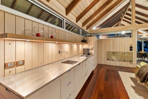 Whangarei HeadsThe Glasshouse的一间铺有木地板的大厨房,配有白色的橱柜
