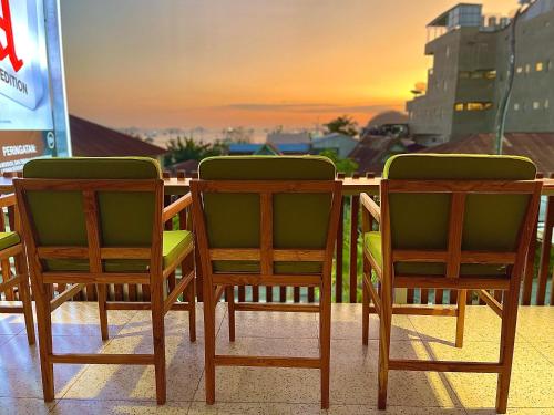 纳闽巴霍Puu Pau Hotel & Coffee Shop的两把椅子和一张桌子,背面是日落