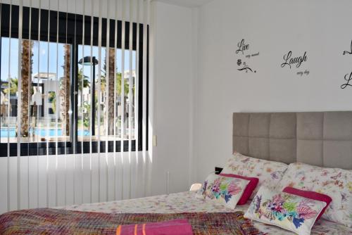 奥里韦拉海滩Casa La Zenia的一间卧室配有带粉红色枕头的床和窗户。