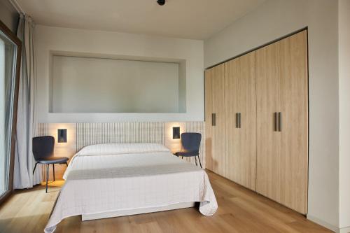 米兰马瑞提那Mima Aparthotel Boutique & Spa的卧室配有一张白色大床和两把椅子