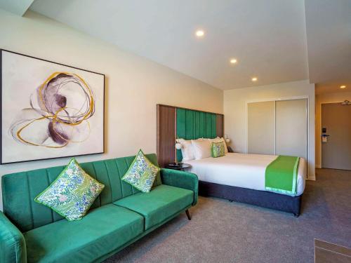 惠灵顿The Sebel Wellington Thorndon的酒店客房,设有一张床铺和一张绿色沙发