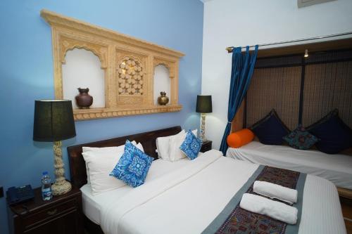 斋沙默尔Hotel Jaisan Haveli的蓝色墙壁客房的两张床