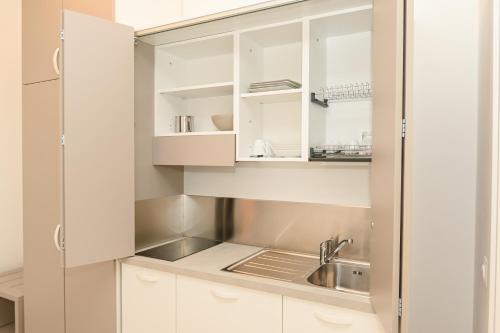 维耶斯泰Agorà Vieste Rooms & Apartments的厨房配有白色橱柜和水槽